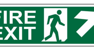 Green FIRE EXIT sign with a running-person symbol and diagonal upward-right arrow by Safe Cure